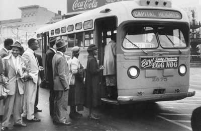 Seven Black men, all dressed in suits, wait in line to board the front of a bus after the decision in Browder v. Gayle.